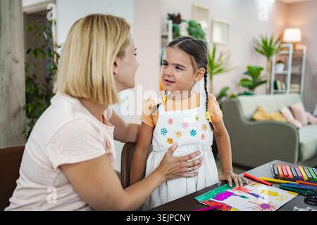 Mamma e figlia condividono un momento di gioia mentre realizzano nel loro accogliente salotto Foto Stock
