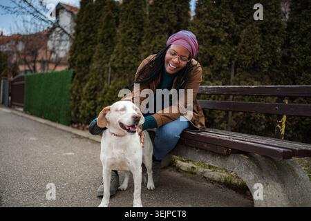 Felice giovane donna adulta che accarezza il cane nel parco Foto Stock