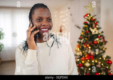 Donna afroamericana sorridente che parla sullo smartphone durante le vacanze Foto Stock