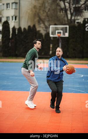 Uomini che giocano a basket all'aperto su un campo urbano Foto Stock