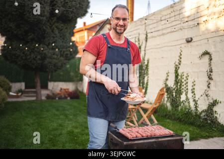 Gustate un barbecue soleggiato con gli amici in un accogliente giardino sul retro Foto Stock