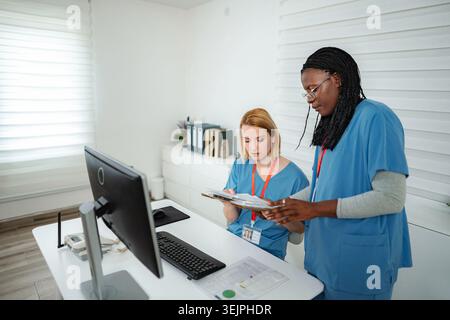 Professionisti medici che collaborano revisione dei documenti del paziente in ufficio clinica Foto Stock