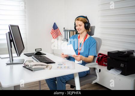 Lavoratrice sanitaria che esamina i documenti in un ufficio di telelavoro Foto Stock