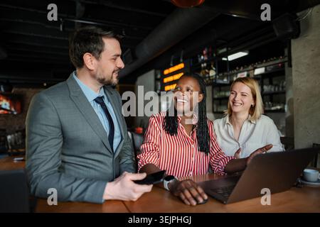 Colleghi aziendali diversi che collaborano e discutono idee in un bar Foto Stock