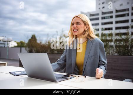 Giovane donna frustrata che fatica a lavorare con un notebook all'aperto Foto Stock
