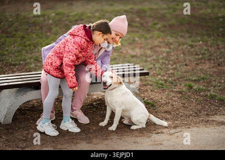 Madre e figlia si legano con il cane felice nel parco Foto Stock