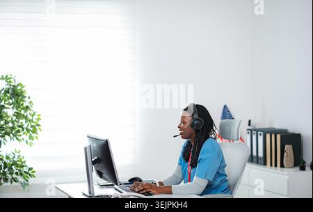 Donna afroamericana che lavora nel call center di telemedicina Foto Stock