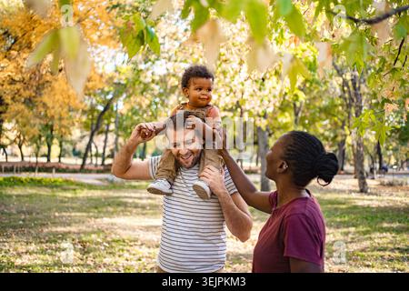 Momenti di gioia in famiglia catturati in un vivace parco autunnale Foto Stock