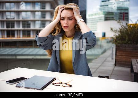 Donna d'affari che soffre di stress, mal di testa e burnout sul tetto urbano Foto Stock