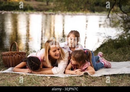 Madre e figlie si divertono ad un picnic sul fiume Foto Stock