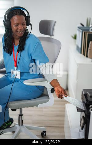 Infermiere che indossa le cuffie utilizzando una stampante in ufficio Foto Stock