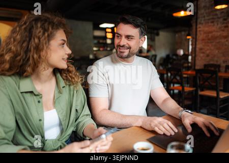 Giovane coppia che lavora su un notebook e ne discute al Cafe Foto Stock