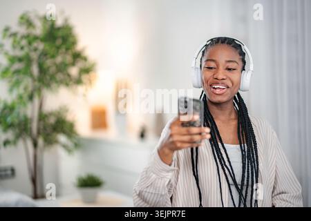 Giovane donna nera che ama la musica sfogliando lo smartphone Foto Stock