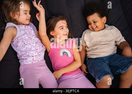 Bambini diversi che sorridono giocando insieme su sfondo scuro Foto Stock