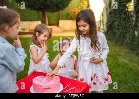 I bambini si divertono con la torta e le risate durante una festa estiva Foto Stock