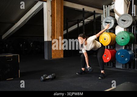 Donna che solleva il manubrio durante l'allenamento in palestra Foto Stock