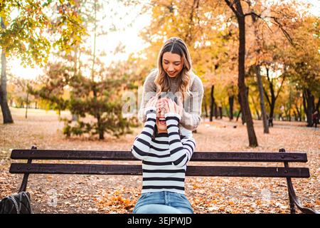 Le bambine si divertono con il caldo abbraccio dell'autunno tra le foglie che cadono Foto Stock