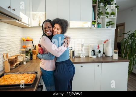 Donne felici che abbracciano la cucina moderna dopo la cottura Foto Stock