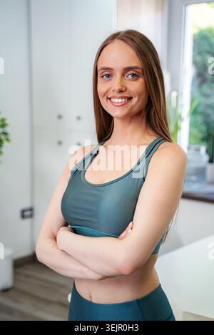 Giovane donna sorridente, in piedi con sicurezza in abbigliamento fitness Foto Stock