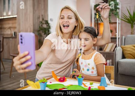 Madre e figlia si godono un momento di gioco mentre fanno un selfie Foto Stock