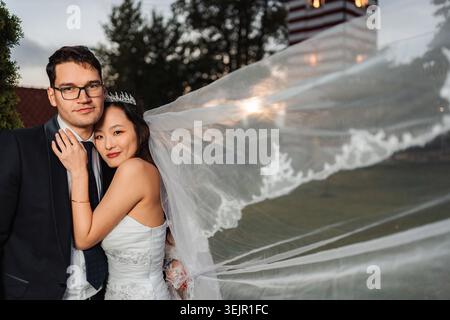 Sposa e sposo che celebrano il ritratto all'aperto del matrimonio interrazziale Foto Stock