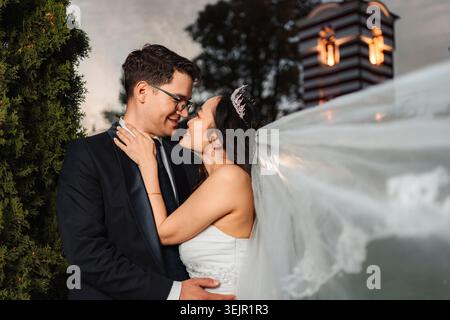 Coppia interrazziale che abbraccia all'aperto durante il giorno del matrimonio Foto Stock