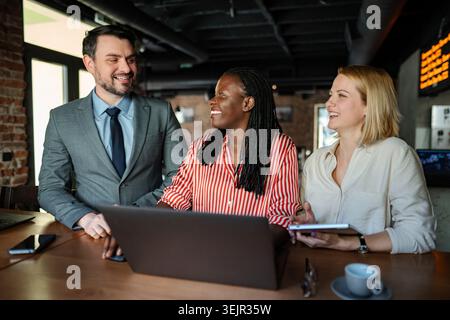 Team aziendali diversificati che collaborano e sorridono durante una riunione informale Foto Stock