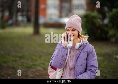 Donna che parla al cellulare sorridendo all'aperto Foto Stock