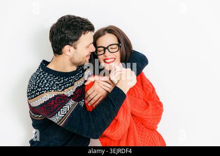 Felice coppia giovane che abbraccia e ride insieme in Studio indossando maglioni caldi romantico Ritratto relazione su bianco Backgro Foto Stock