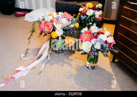 Mazzi di matrimoni colorati con nastri disposti in vasi di vetro al piano della camera dell'hotel Foto Stock