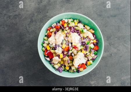 Insalata di verdure tritata con cavolfiore, cavolo, cetriolo e peperoni in un recipiente verde Foto Stock