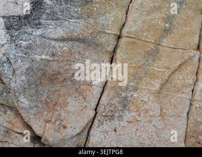 Primo piano orizzontale di un'ampia superficie di massi intemprati con ampie crepe, sfumature di roccia multicolore dal nero all'abbronzatura al rosso, consistenza porosa ruvida Foto Stock