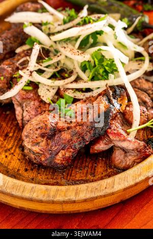Shashlik tradizionale servito con peperoni grigliati, cipolla a fette ed erbe fresche su un piatto di legno, Azerbaijan. Foto Stock