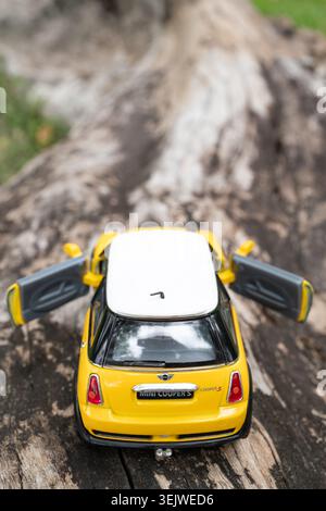 Chiang mai, Tailandia - 25 maggio 2026 : La mini Cooper S gialla in metallo pressofuso, vista posteriore dall'alto, porte aperte sul tronco dell'albero caduto all'aperto Foto Stock