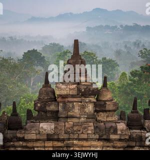 Le eccezionali Stupas del Tempio Borobudur a Yogyakarta, all'alba, sovrastano un paesaggio nebbioso della giungla Foto Stock