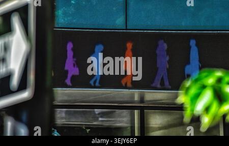 Le figure al neon ballano lungo il muro di un edificio Foto Stock