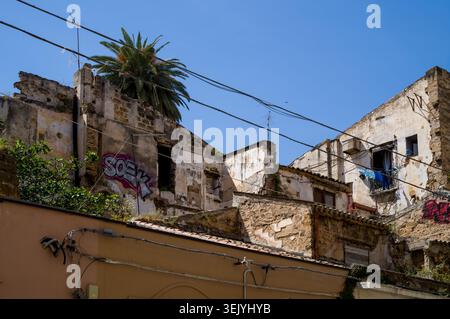 In Sicilia, gli edifici in rovina mostrano segni di abbandono. I graffiti segnano le pareti sbriciolate, ma il bucato è appeso all'esterno, mostrando che la vita si perde Foto Stock