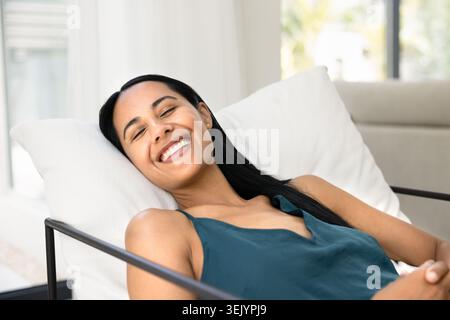 Donna felice che si rilassa sulla sedia a casa, primo piano Foto Stock