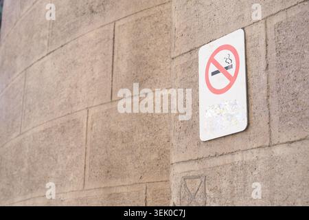 Cartello vietato fumare su un muro di mattoni in uno spazio pubblico Foto Stock