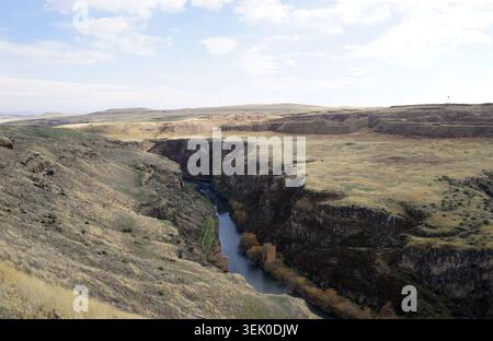 Il fiume Akhuryan scava una gola a pareti ripide attraverso il vasto plateau arido lungo il paesaggio di confine vicino alle antiche rovine di Ani a Kars, Turchia Foto Stock