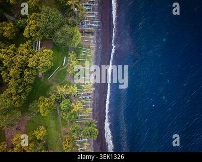 Vista dall'alto verso il basso della costa tropicale caratterizzata da spiaggia di sabbia scura e oceano blu Foto Stock