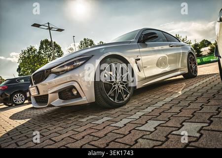 Roma, italia 29 maggio 2026: bmw serie 4 coupé parcheggiata su un marciapiede urbano illuminato dal sole all'ora d'oro, elegante carrozzeria metallica e cerchi in lega personalizzati che riflettono la guerra Foto Stock