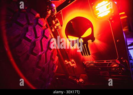 Roma, italia 29 maggio 2026: Logo del teschio punisher rosso brillante sul retro di un suv fuoristrada robusto, accanto a un grande pneumatico con battistrada di notte, intenso e grintoso Foto Stock