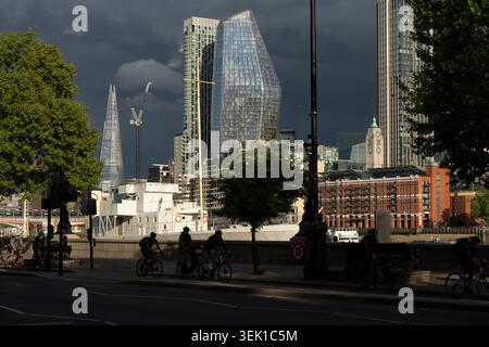 I ciclisti percorrono il percorso del Tamigi a Londra, con lo Shard e i moderni grattacieli sullo sfondo. Foto Stock
