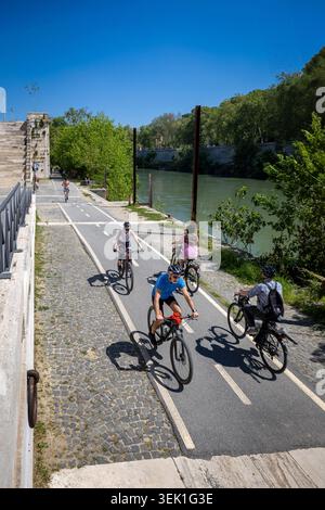 Roma, Italia - 19 aprile 2026: Un gruppo di persone in bicicletta sulla pista ciclabile asfaltata che corre lungo le rive del Tevere in una giornata di sole. Il Foto Stock