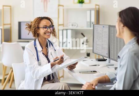 Medico donna che esamina le registrazioni dei pazienti e le opzioni di trattamento durante la visita clinica Foto Stock
