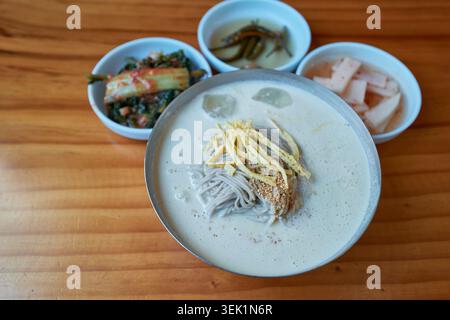 Coreano Memil Kongguksu, spaghetti freddi di grano saraceno in cremoso brodo di soia. Condito con guarnigione di uova e servito con contorni per un sano pasto estivo. Foto Stock