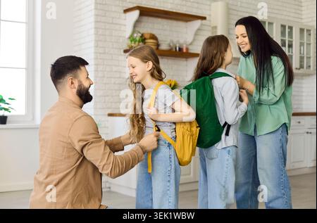 I genitori preparano le figlie con gli zaini a casa prima della scuola, buon giorno Foto Stock