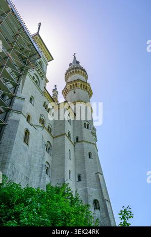 Schwangau, Germania - maggio 31 2026: Vista dall'angolo basso della storica torre del castello di Neuschwanstein con impalcature di costruzione sulla facciata sinistra sotto a. Foto Stock