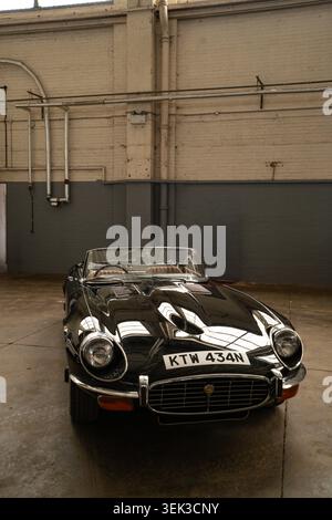 Black Jaguar e-Type serie 3 V12 Roadster KTW 434N parcheggiata all'interno di un edificio industriale alla fiera Bicester Foto Stock